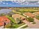 An aerial view of a community with lake, and single-Gathering homes, showcasing their tile roofs, driveways and landscaping at 20211 Granlago Dr, Venice, FL 34293