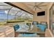 Covered patio with a ceiling fan, TV, and seating overlooking the pool and lake at 20211 Granlago Dr, Venice, FL 34293