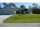 Beautifully landscaped home featuring a well-manicured lawn, elegant driveway, and a charming light-blue exterior at 380 Hoffer St, Port Charlotte, FL 33953