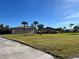 Spacious front lawn featuring palm trees and a charming single-story home under a clear blue sky at 9822 Gulfstream Blvd, Englewood, FL 34224