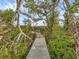 Scenic wooden walkway through lush greenery leading to serene waterfront and nature views at 7475 Manasota Key Rd, Englewood, FL 34223