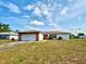 Single story home featuring an attached garage, red trim, and a lawn at 914 E 2Nd St, Englewood, FL 34223