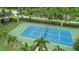 Aerial view of community tennis court with green and blue surfaces, palm trees, and landscaping at 10360 Longshore Rd # 66, Placida, FL 33946