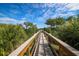 Wooden boardwalk surrounded by lush greenery and palm trees, leading towards a scenic view at 10360 Longshore Rd # 66, Placida, FL 33946