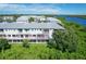 Exterior view of condo building with balconies overlooking green space and a waterway in the distance at 10360 Longshore Rd # 66, Placida, FL 33946