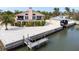 Exterior view of a two-story home featuring a boat lift, with a balcony, large windows, and lush landscaping at 2805 N Beach Rd # B, Englewood, FL 34223