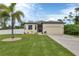 Well-maintained single-story home with a two car garage, lush lawn and a beautiful palm tree at 108 Wagon Place, Rotonda West, FL 33947
