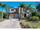 Inviting two-story home featuring a stone facade, paver driveway, and lush tropical landscaping at 117 Cable Dr, Rotonda West, FL 33947
