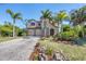 Beautifully landscaped home with a stone facade, paved driveway, and mature palm trees at 117 Cable Dr, Rotonda West, FL 33947