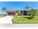 Charming single-story home boasting an attached two-car garage, lush lawn, and mature palm trees at 214 W Pine Valley Ln, Rotonda West, FL 33947