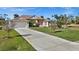 Inviting single-story home featuring a well-maintained lawn, mature landscaping and a long driveway leading to an attached garage at 411 Boundary Blvd, Rotonda West, FL 33947