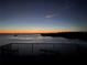 View of a sunset over the bay from the backyard with a metal fence at 7180 Brittany Cir, Englewood, FL 34224