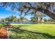 Scenic lake view with mature trees, seating, and lush green lawn at 891 Harmony Ln, Englewood, FL 34223