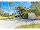 Spacious backyard with lush landscaping, tall palm trees, and a shed, ideal for outdoor activities at 891 Harmony Ln, Englewood, FL 34223