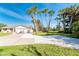 Inviting home exterior with a driveway, lush lawn, and tall palm trees set against a bright blue sky at 891 Harmony Ln, Englewood, FL 34223