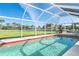 Beautiful in-ground pool with screened enclosure, spacious patio, and serene water view at 891 Harmony Ln, Englewood, FL 34223
