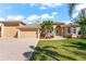 Stunning single-story tan home with a tile roof, arched entryway, attached garage, and beautifully landscaped front yard at 10544 Poughkeepsie Cir, Port Charlotte, FL 33981