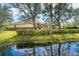 Landscaped backyard, partially obscured by trees, has a screened-in lanai and pond view at 12650 Montigello Ct, Englewood, FL 34223