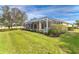 Backyard features lush grass, a screened-in lanai, and landscaped garden beds surrounding the pool area at 12650 Montigello Ct, Englewood, FL 34223