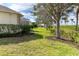 Well-manicured backyard featuring lush green grass, mature trees, and privacy hedges at 12650 Montigello Ct, Englewood, FL 34223