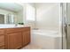 Bathroom featuring soaking tub, glass-enclosed shower, and wood vanity at 12650 Montigello Ct, Englewood, FL 34223