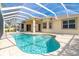 Backyard pool area with a clear blue pool, covered lanai, and lush green landscaping at 12650 Montigello Ct, Englewood, FL 34223