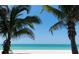 White sand beach framed by lush palm trees under a clear blue sky with ocean views at 2814 Vogler Ln, North Port, FL 34286