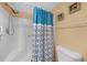 Close up of a step-in shower with blue decorative curtain, and a shower head at 3310 Loveland Blvd # 802, Punta Gorda, FL 33980