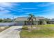 Charming single-story home features a well-manicured lawn, palm tree, and an inviting front porch seating area at 7586 Sea Mist Dr, Port Charlotte, FL 33981