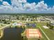 Aerial view showcasing the community tennis courts, lake, swimming pool, and clubhouse at 13532 Romford Ave, Port Charlotte, FL 33981