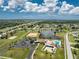 Wide aerial view of community amenities including tennis, pickleball and shuffleboard courts, clubhouse and pool at 13532 Romford Ave, Port Charlotte, FL 33981