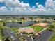 Aerial view of community featuring a lake, tennis courts, clubhouse, pool, and ample parking at 13532 Romford Ave, Port Charlotte, FL 33981