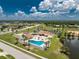 Broad aerial shot featuring a community with a pool, clubhouse, and tennis courts by a lake at 13532 Romford Ave, Port Charlotte, FL 33981