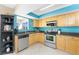 The kitchen features stainless steel appliances, wood cabinets, and a stylish blue accent wall at 13532 Romford Ave, Port Charlotte, FL 33981
