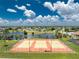 Aerial view of the community's orange and yellow fenced tennis courts next to lake at 13532 Romford Ave, Port Charlotte, FL 33981
