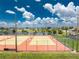 Community tennis courts with orange fencing, lights, bench, and the community's lake at 13532 Romford Ave, Port Charlotte, FL 33981