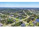 Expansive aerial view of a residential neighborhood with manicured lawns, tree-lined streets, and community waterways under a clear sky at 252 Australian Dr, Rotonda West, FL 33947
