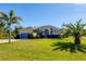 Inviting home with a lush green lawn, established palm trees, and manicured shrubbery at 252 Australian Dr, Rotonda West, FL 33947
