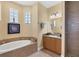 Main bathroom features a soaking tub, vanity with granite countertop, and glass block windows at 252 Australian Dr, Rotonda West, FL 33947