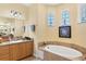 Main bathroom features a soaking tub, vanity with granite countertop, and decorative artwork at 252 Australian Dr, Rotonda West, FL 33947