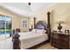 Well-lit main bedroom showcasing a king-size bed, dark wood furniture, and tray ceilings at 252 Australian Dr, Rotonda West, FL 33947