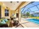 Covered patio with comfortable seating, overlooking a screened-in pool and lush landscaping. Perfect for outdoor relaxation and entertaining at 252 Australian Dr, Rotonda West, FL 33947
