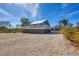 Coastal home featuring a breezy wraparound deck, durable metal roof, and ample parking on a shell-covered lot under blue skies at 331 Bocilla Dr, Placida, FL 33946