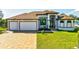 Beautiful new home with a brick paver driveway, a well-manicured lawn, and a three-car garage at 9533 Arnaz Cir, Port Charlotte, FL 33981