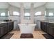 Luxurious bathroom with a freestanding tub, dual vanities, and arched windows for natural light at 9533 Arnaz Cir, Port Charlotte, FL 33981