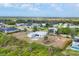 An aerial view of a light-blue, single-story home in a quiet neighborhood with green space and blue skies at 10307 Grail Ave, Englewood, FL 34224