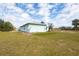 Back of house with lush green lawn and sunny skies at 10307 Grail Ave, Englewood, FL 34224