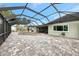 Enclosed pool area with grey brick floor, open pool and metal screening under a bright blue sky at 232 Bahia Vista Dr, Englewood, FL 34223