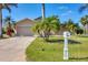 Inviting single-story home featuring a lush front lawn, charming mailbox, and a spacious driveway leading to a garage at 100 Hobo Rd, Rotonda West, FL 33947