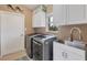 Modern laundry room with stainless steel washer and dryer, storage cabinets, and utility sink at 100 Hobo Rd, Rotonda West, FL 33947